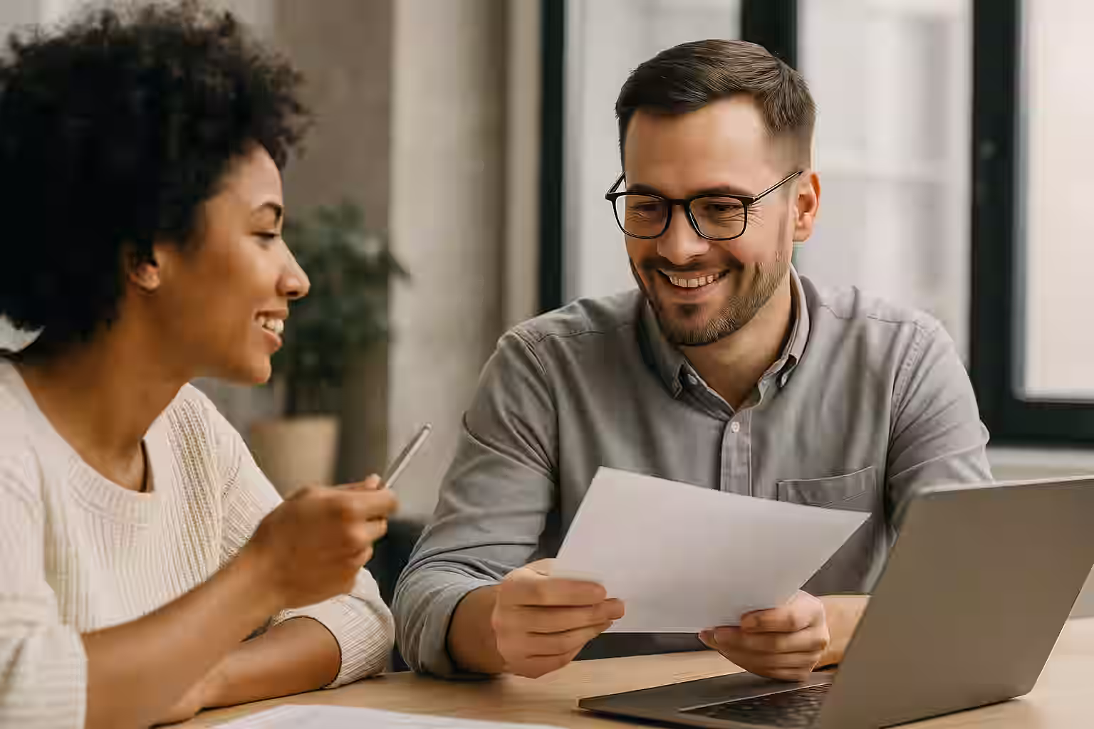 A photograph features a young professional in a modern workspace typing on a laptop, appearing focused and thoughtful — representing the act of sending suggestions or constructive feedback.